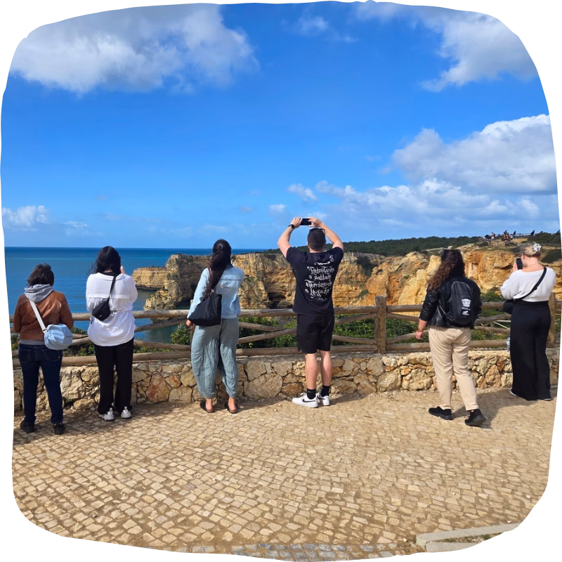 Group of travellers enjoying the breathtaking panoramic view from Praia da Marinha viewpoint, overlooking golden cliffs and turquoise waters on our best Algarve coast tour from Faro.